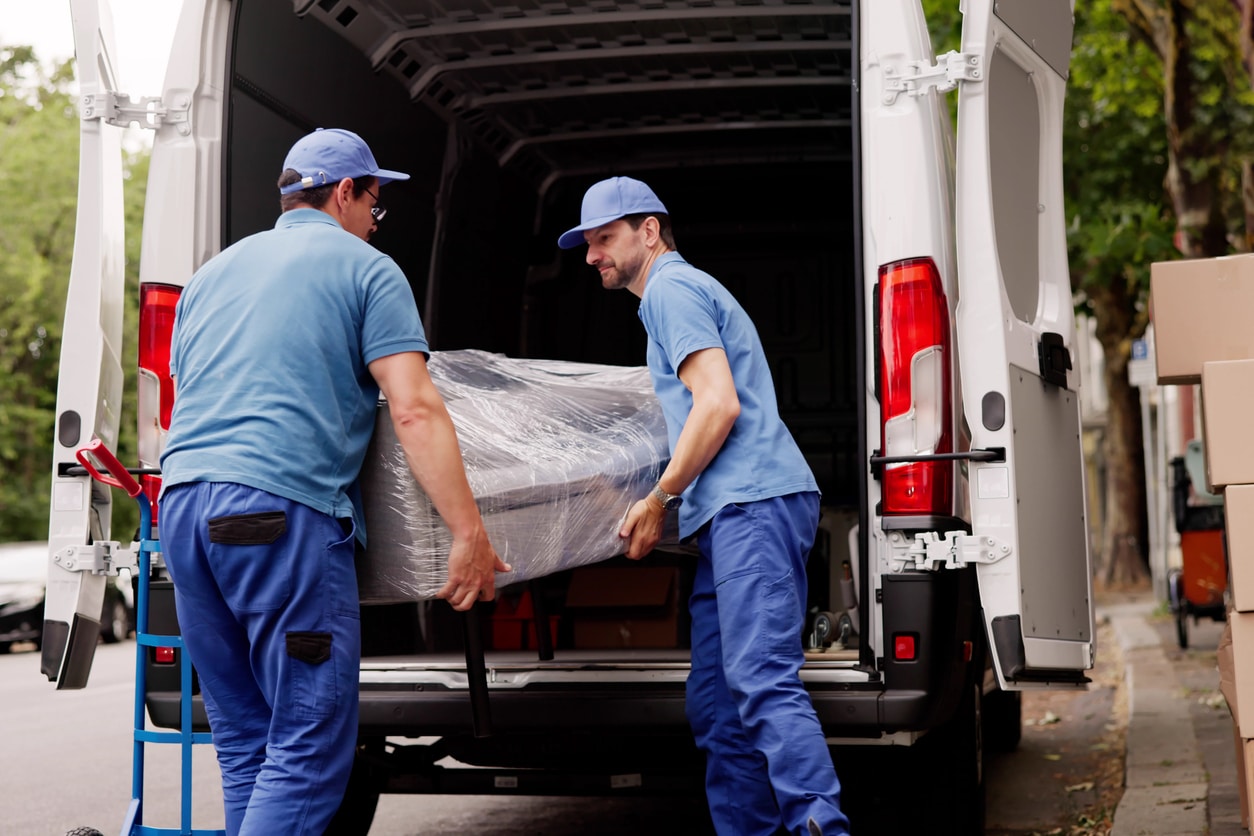 Full-service movers loading a wrapped couch onto a moving truck for customers who are moving into an apartment