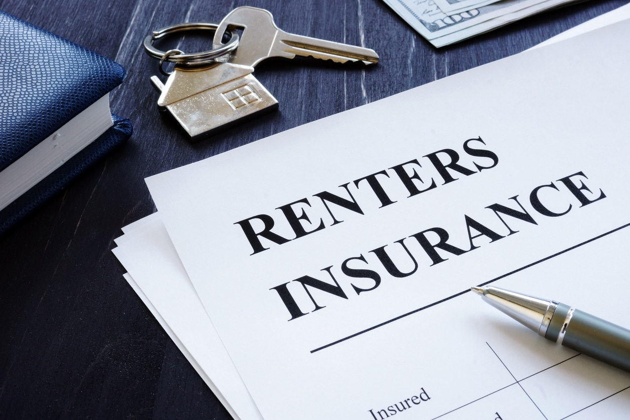 A document that says “renters insurance” next to a pair of house keys for moving to a new apartment