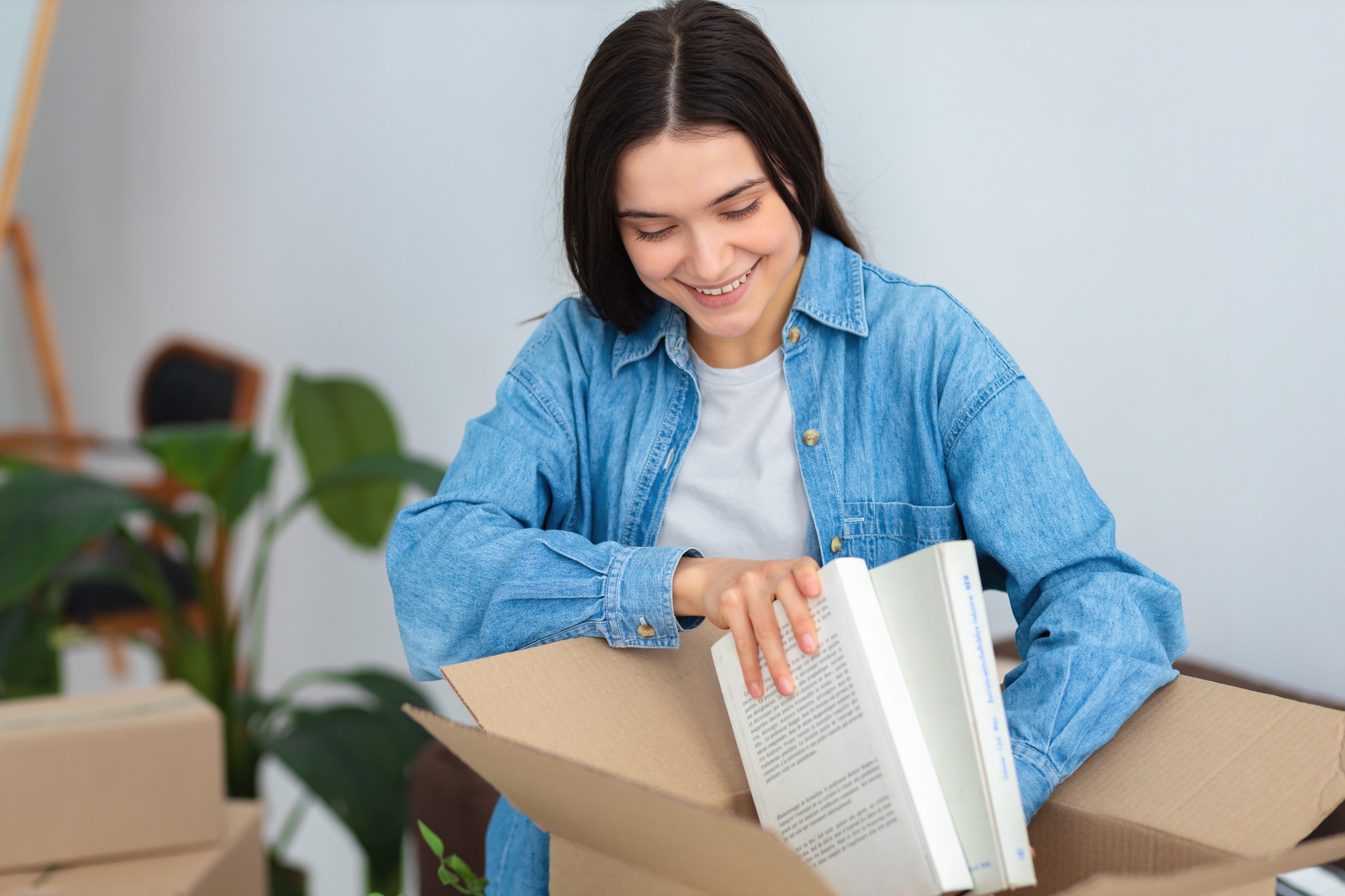 A lady carefully packs her books into a moving box, demonstrating how to pack books for moving