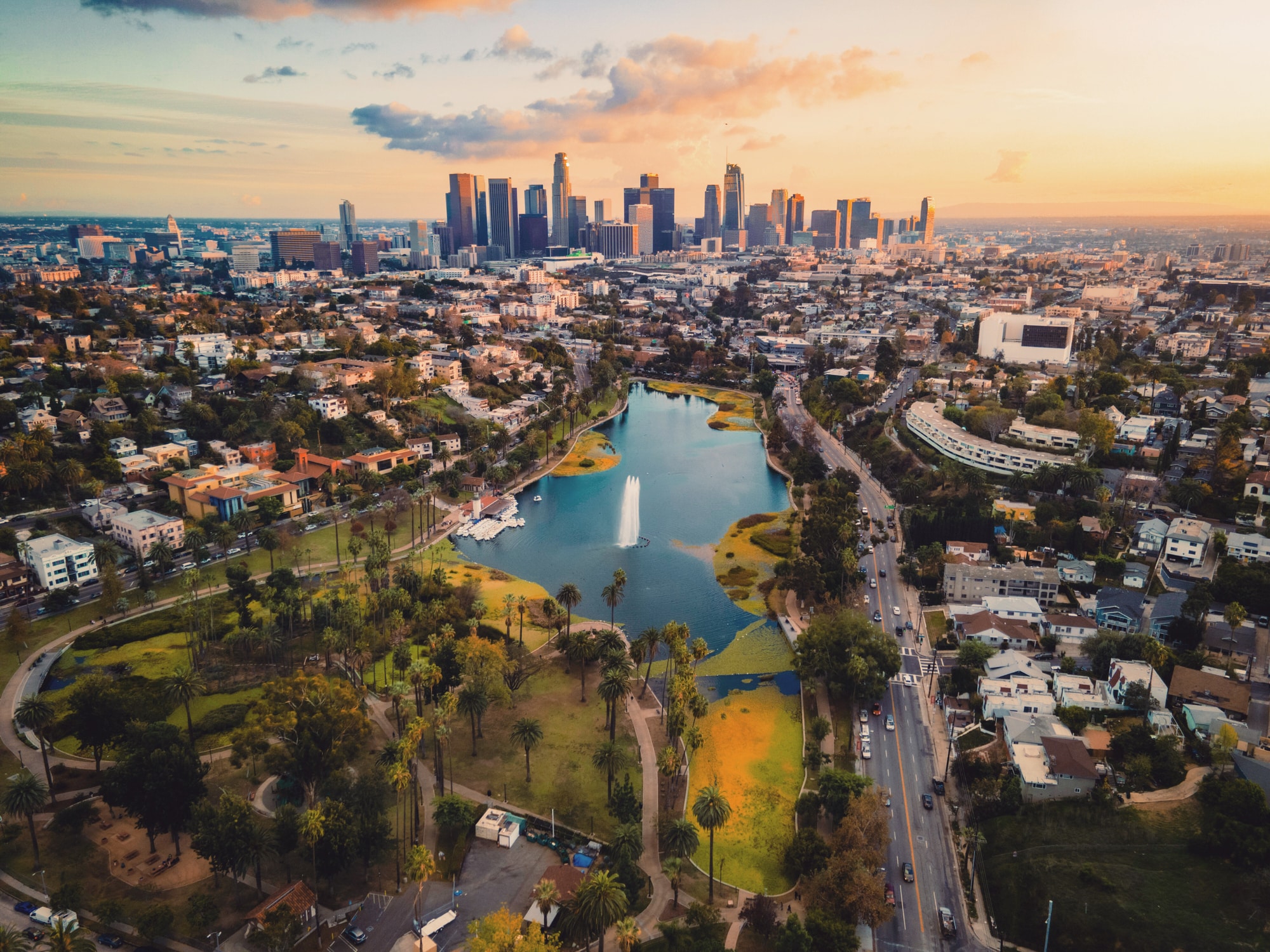 Aerial view of Los Angeles, California, at sunset, featuring Echo Park Lake and the downtown skyline in the background