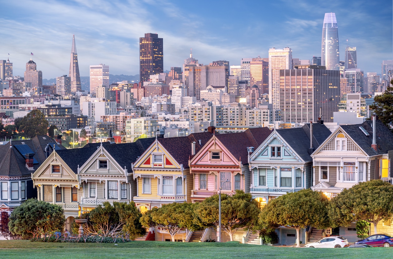 Colorful Victorian Painted Ladies in San Francisco with the city skyline and trees in the foreground