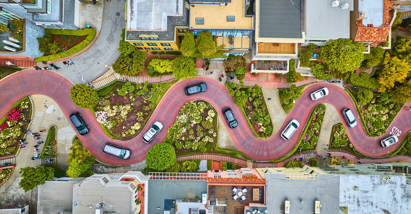 Aerial view of San Francisco's crooked Lombard Street with cars navigating its famous hairpin turns amidst lush greenery