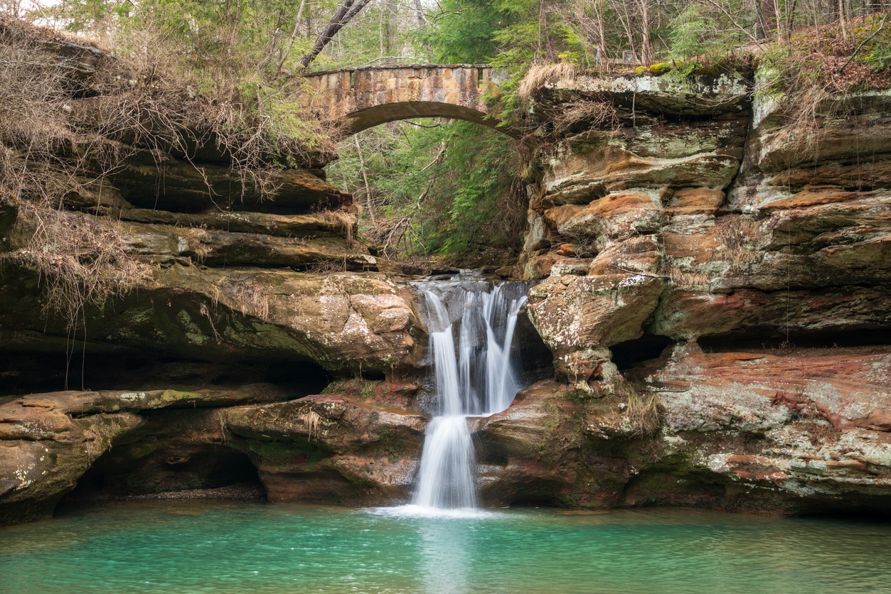 A Waterfall at Hocking Hills State Park in the Hocking Hills region of Hocking County, Ohio, United States Scenic Upper Falls at Old Man's Cave in Hocking Hills, featuring a stone bridge over a waterfall and turquoise pool