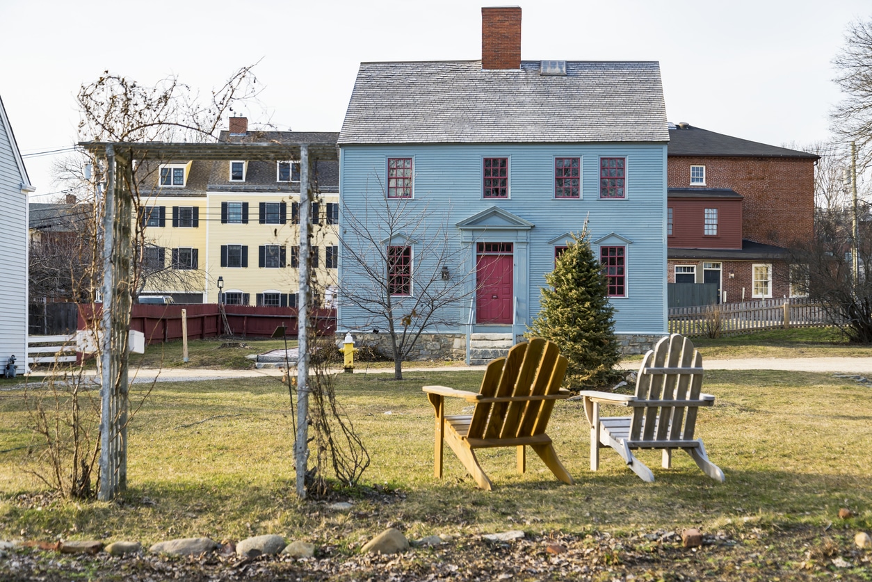 old buildings in the city of Porthsmouth NH, USA Two Adirondack chairs on a lawn facing a historic blue house in a charming New Hampshire neighborhood