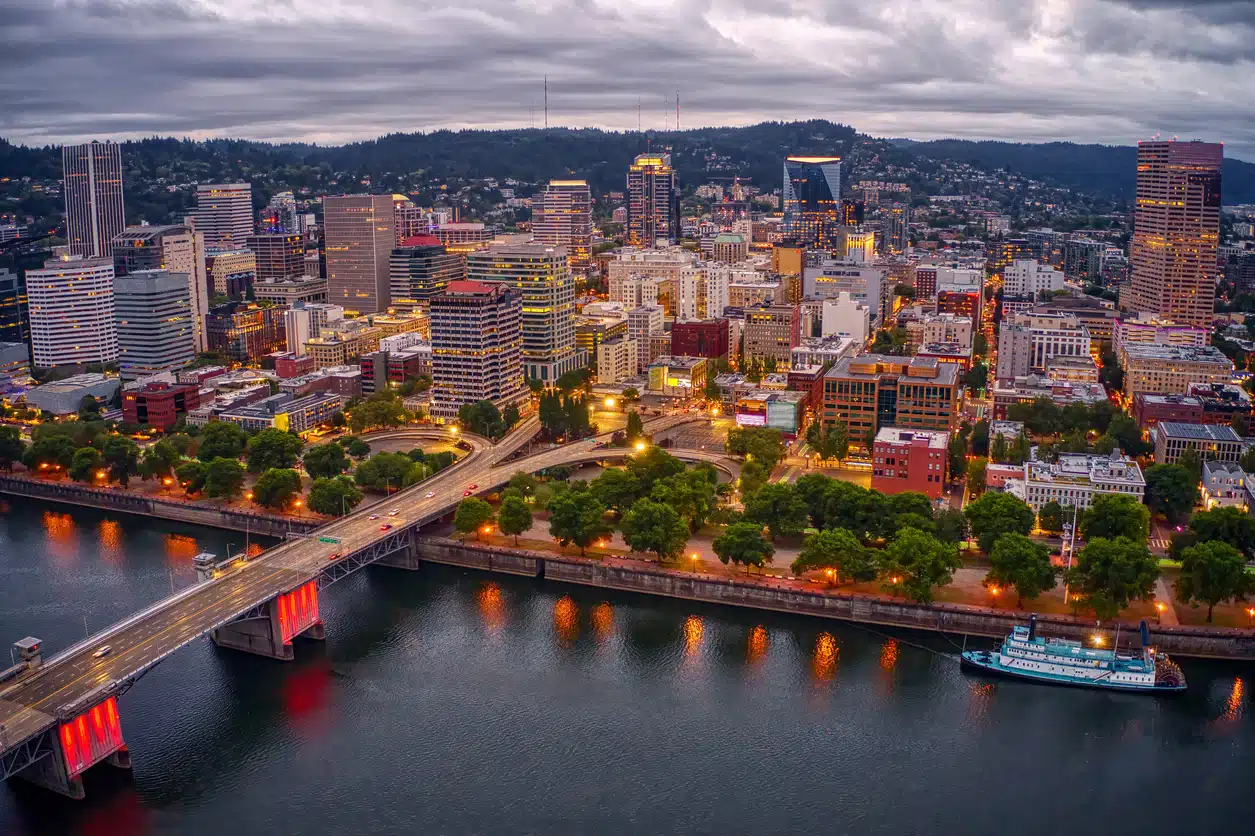 Portland skyline at dusk with river reflections, bridges, and illuminated buildings