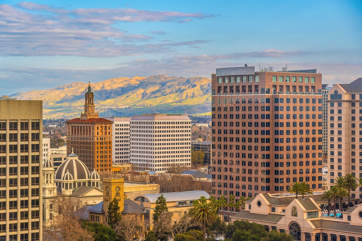 The San Jose skyline at sunset with mountains in the background and city buildings in the foreground