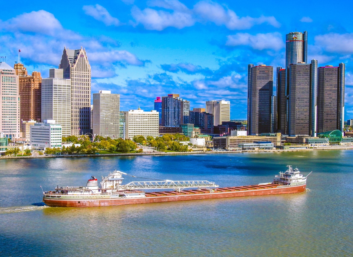 Detroit city skyline at sunset with the Renaissance Center, tall buildings, riverboat, and Detroit River