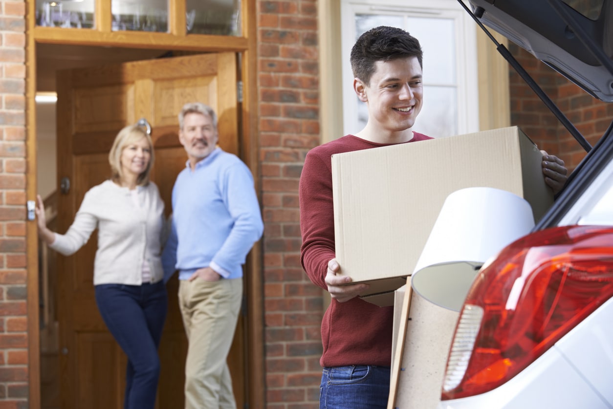 Adult Son Moving Out Of Parent's Home A young man packing his car as he gets ready to move away from his family, who’s watching him from the front door