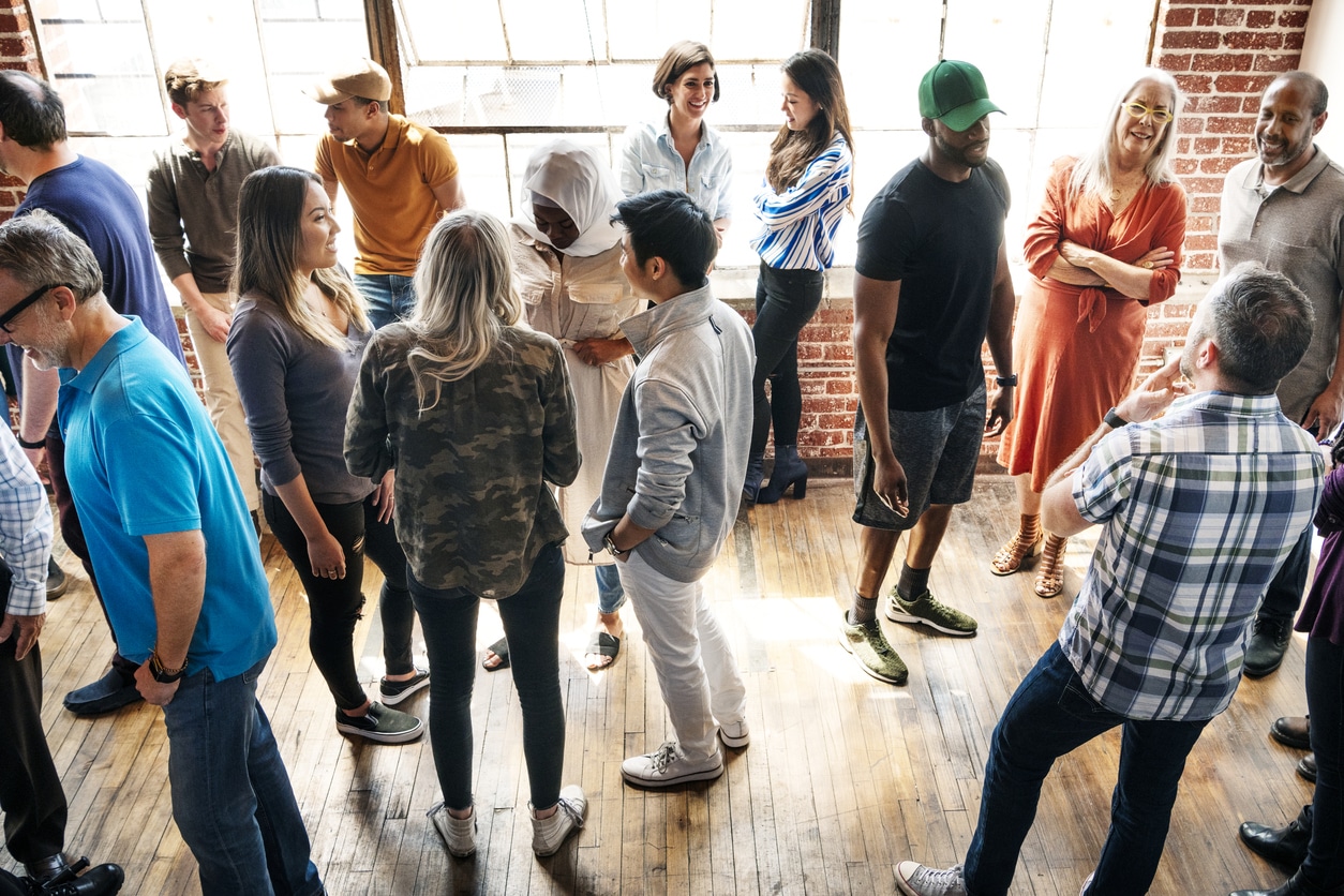 Group of diverse people in a workshop A gathering of people of all ages in brick-walled meeting space getting to know new people after moving