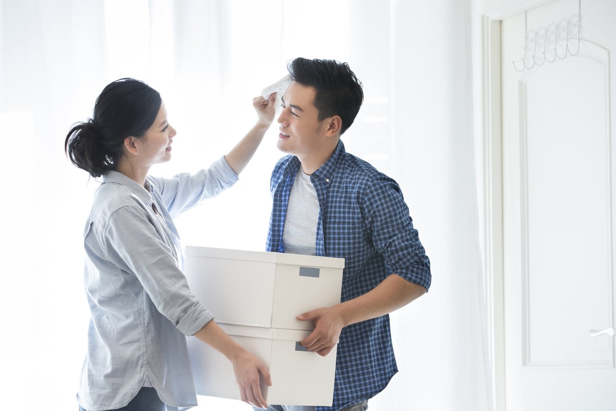 Young couple taking a break from summer moving and wiping the sweat off his face