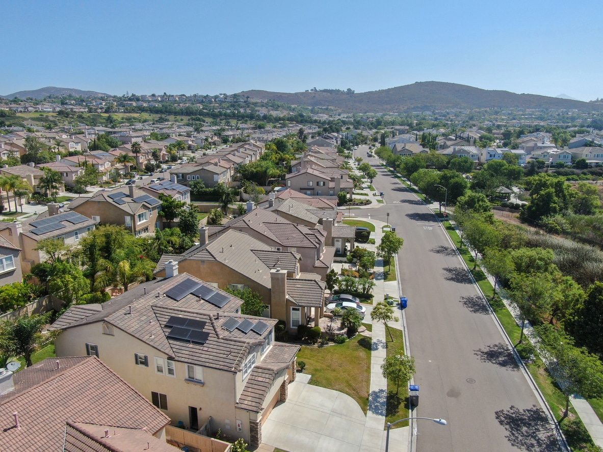 Californian Suburban neighborhood street with big villas Aerial view of a sunny suburban neighborhood with houses, streets, solar panels, and distant hills