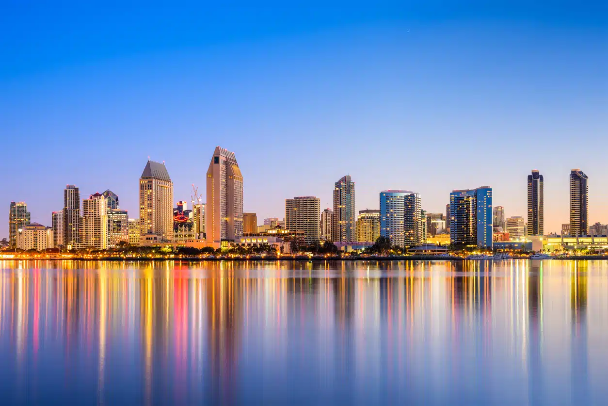 San Diego skyline at dusk reflected in the water, with city lights illuminating the buildings and waterfront
