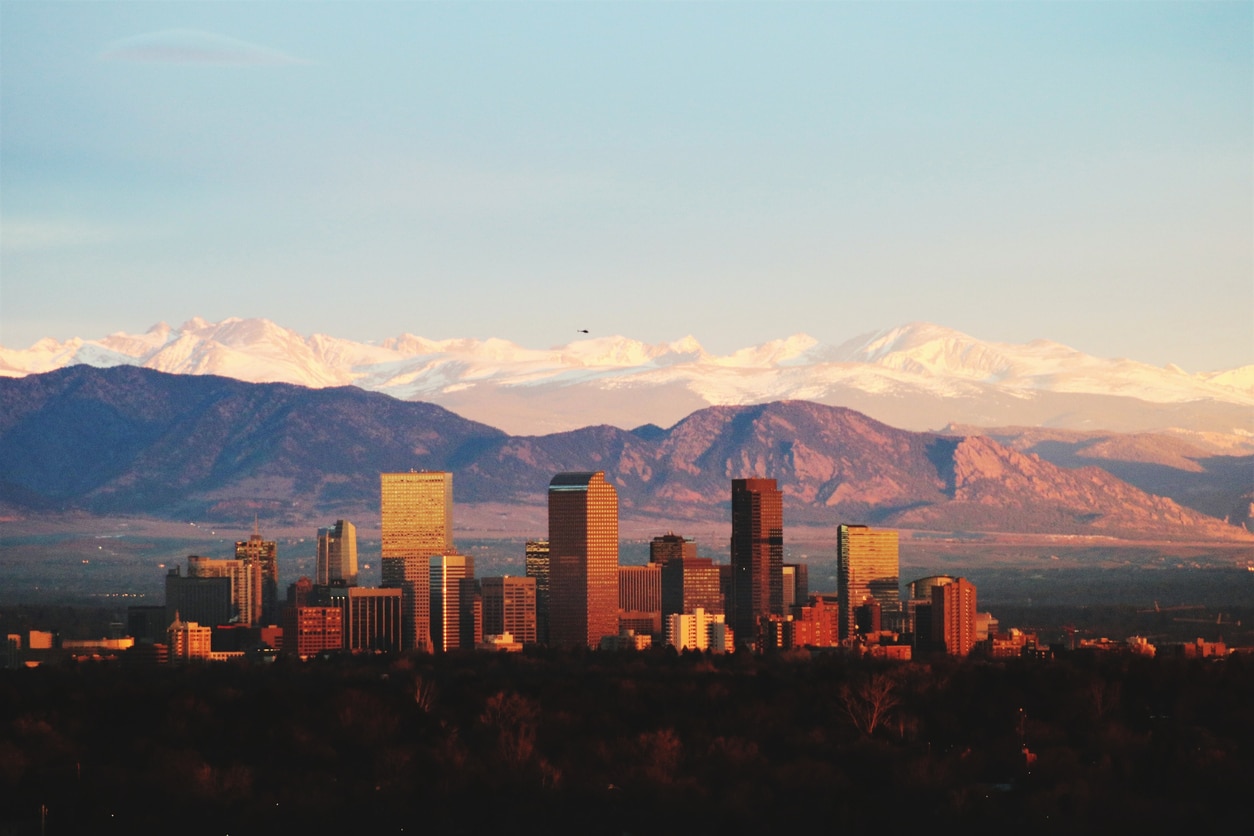 Denver skyline at sunset with the snow-capped Rocky Mountains in the background