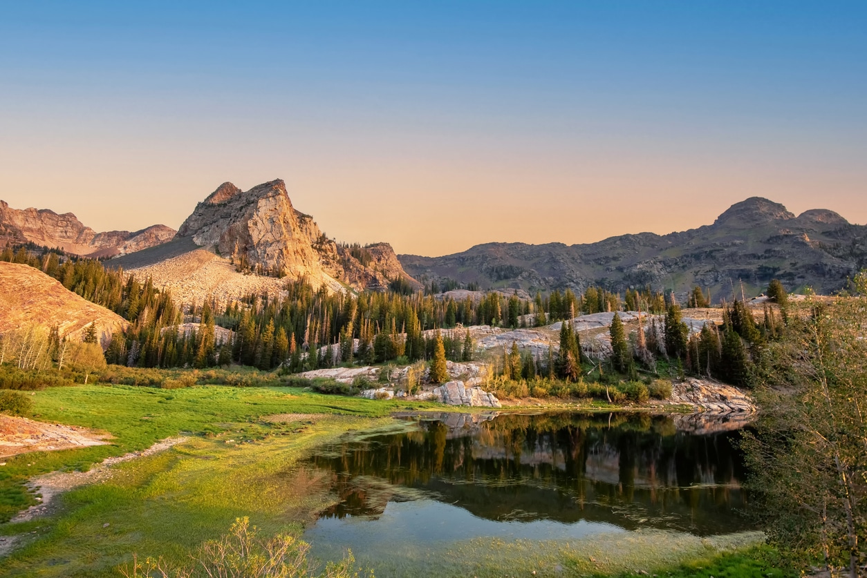 Lake Blanche in Utah's Wasatch Mountains, with Sundial Peak reflected in the alpine lake surrounded by evergreen trees