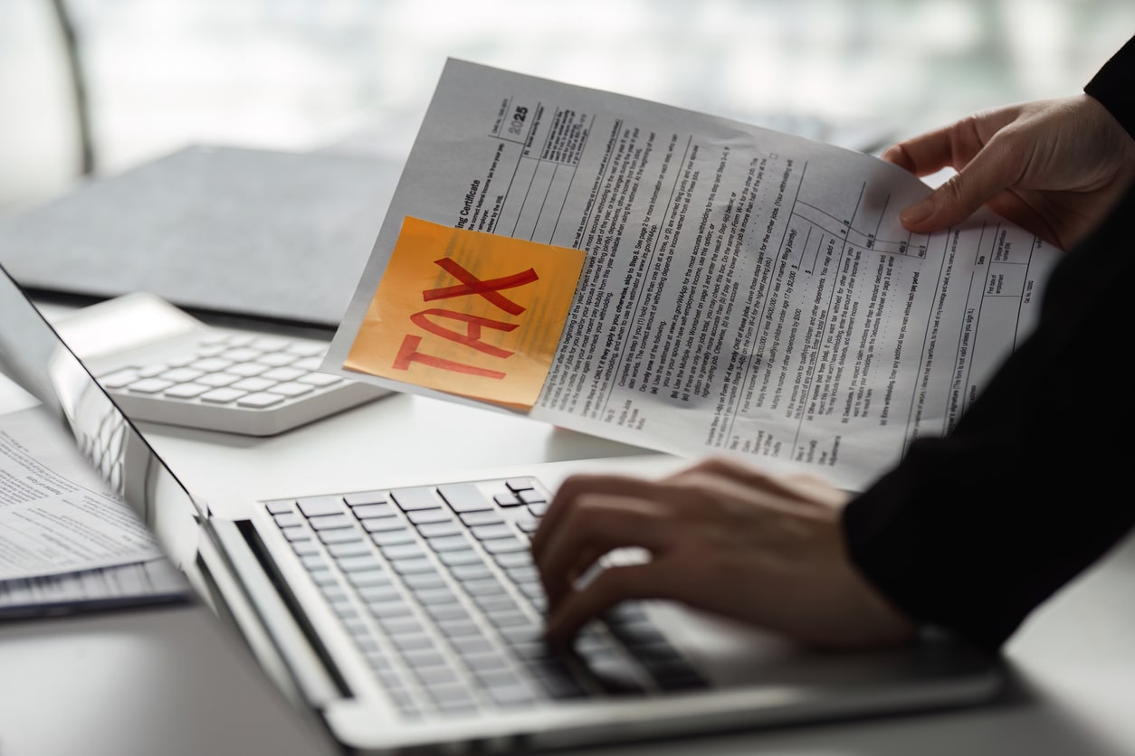 Hands hold a tax document as someone looks into whether or not their moving expenses are tax-deductible