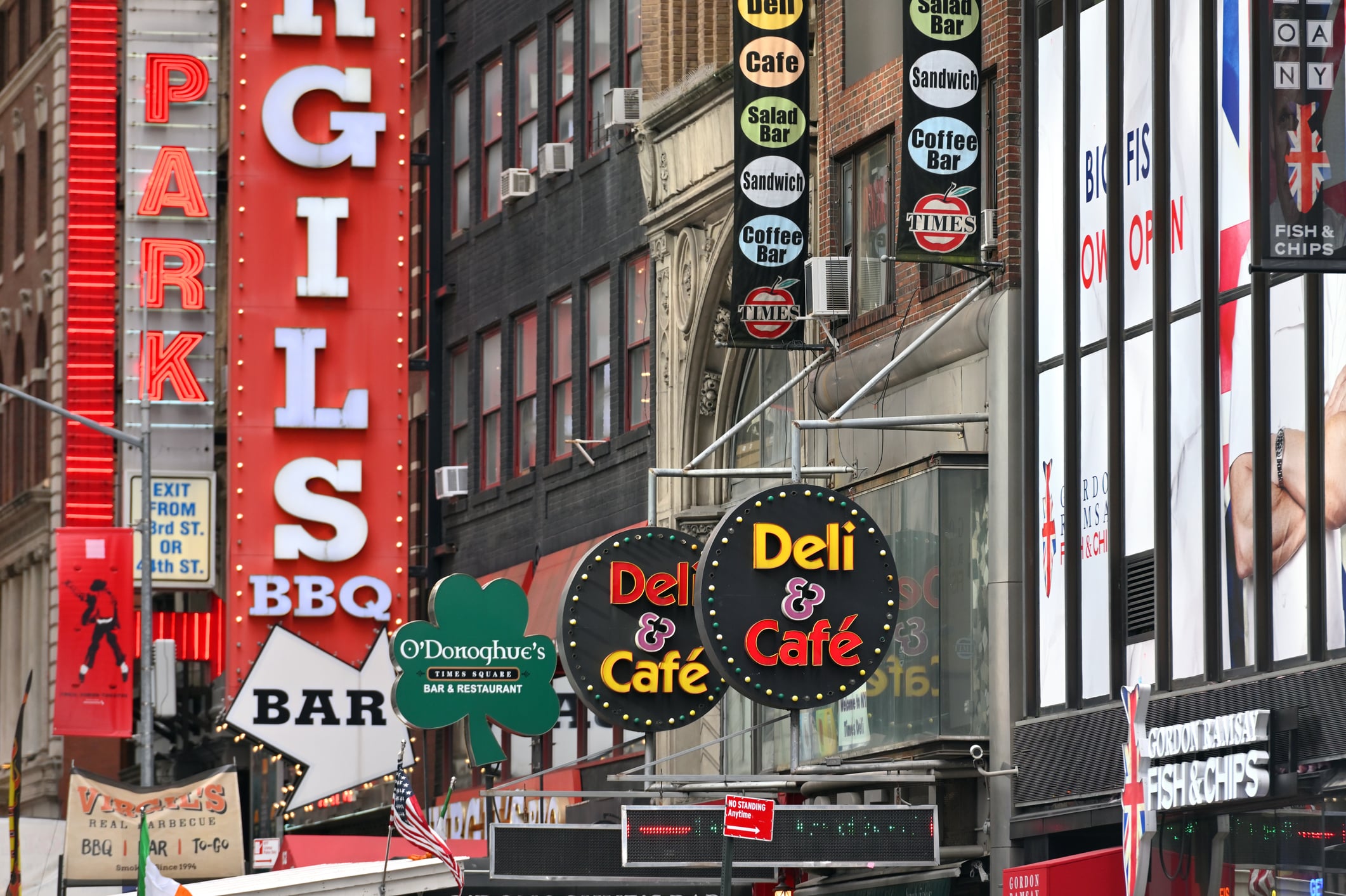 Street view of a bustling Manhattan neighborhood, showcasing vibrant cafes, delis, and restaurants