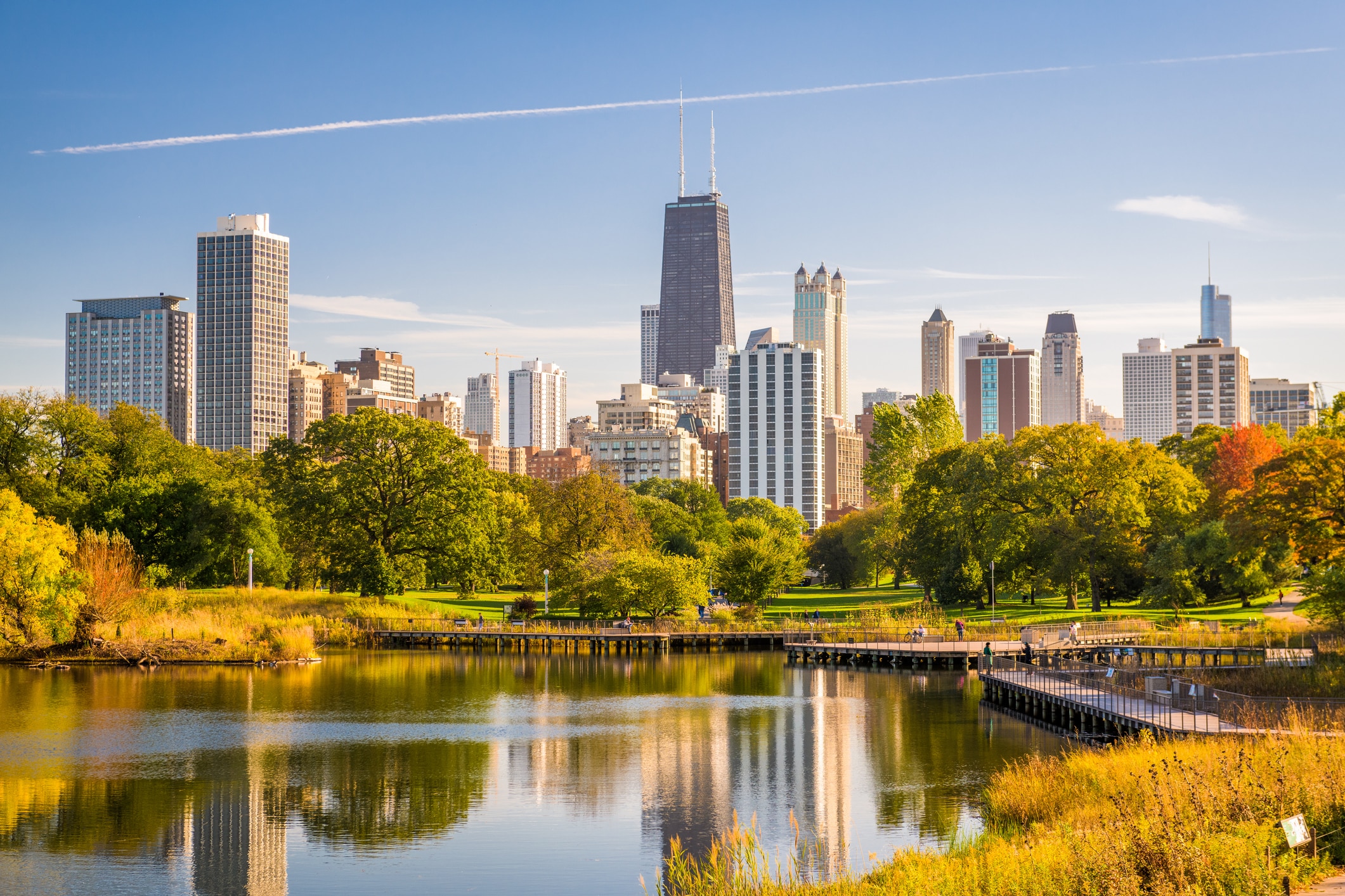 Chicago skyline with a lake and greenery in the foreground seen from Lincoln Park, one of the best neighborhoods in Chicago