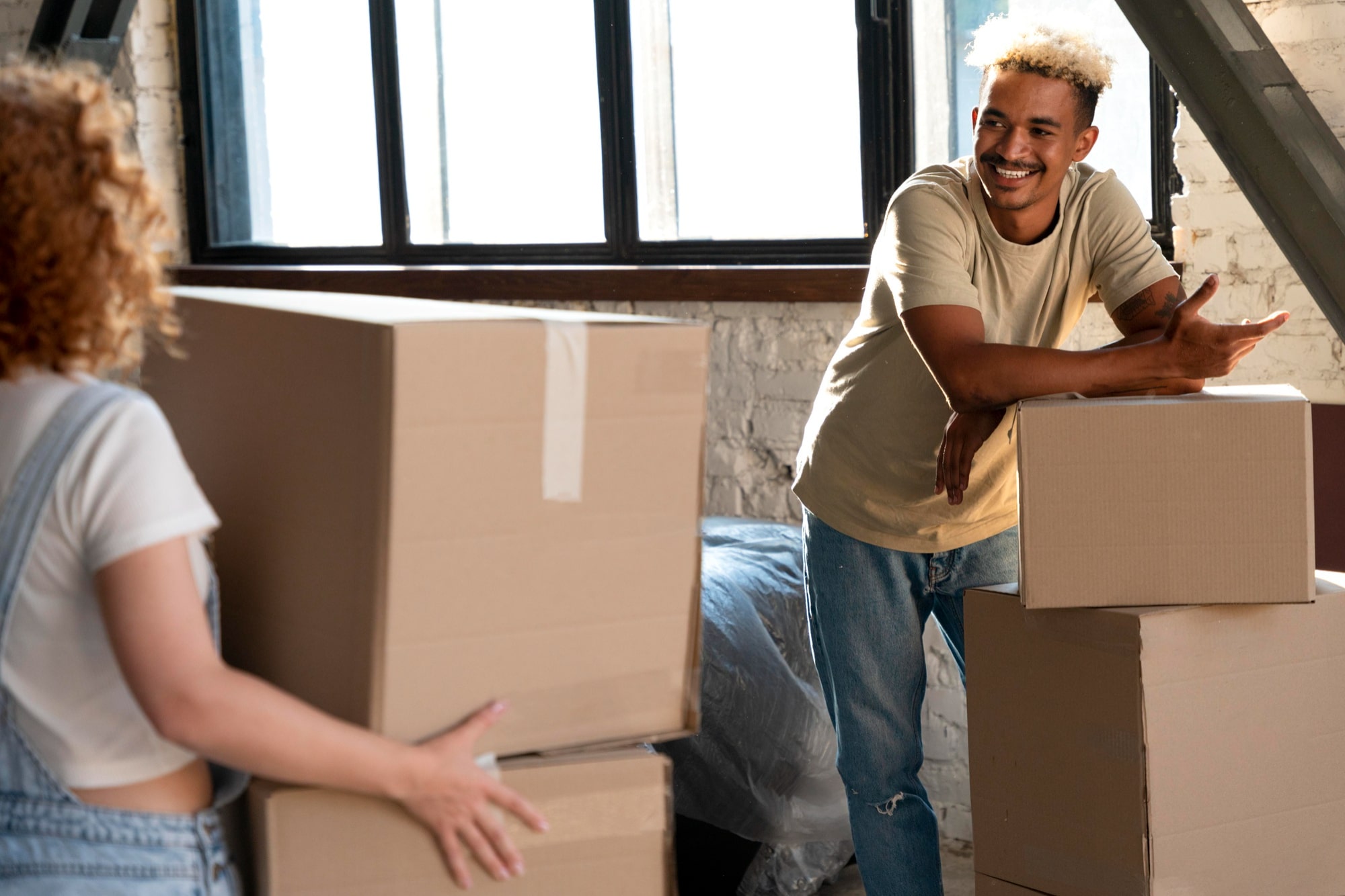 A couple happily sorting their moving boxes for moving from California to New York