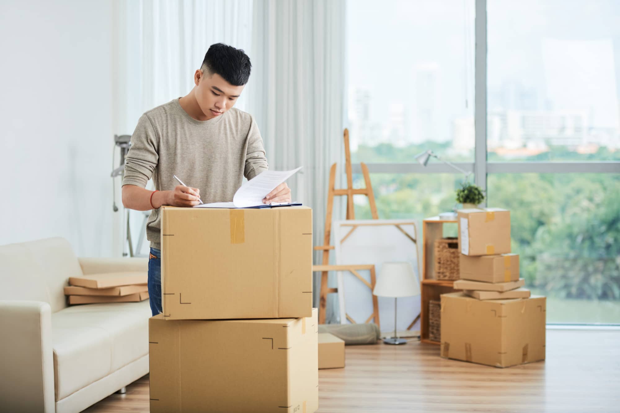 A man surrounded by moving boxes, preparing to move from New York to California