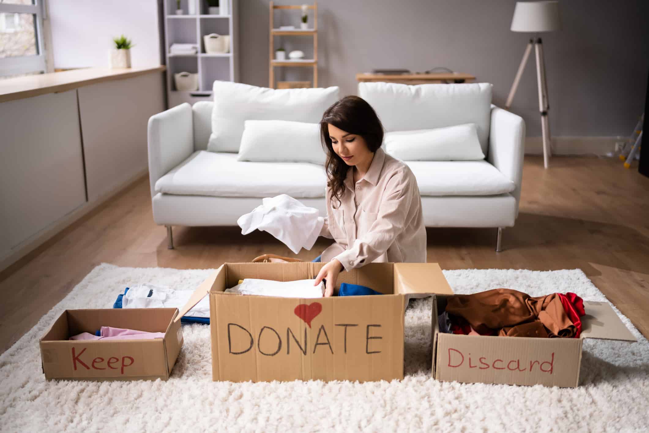 A woman decluttering and sorting her used clothes before moving out of state