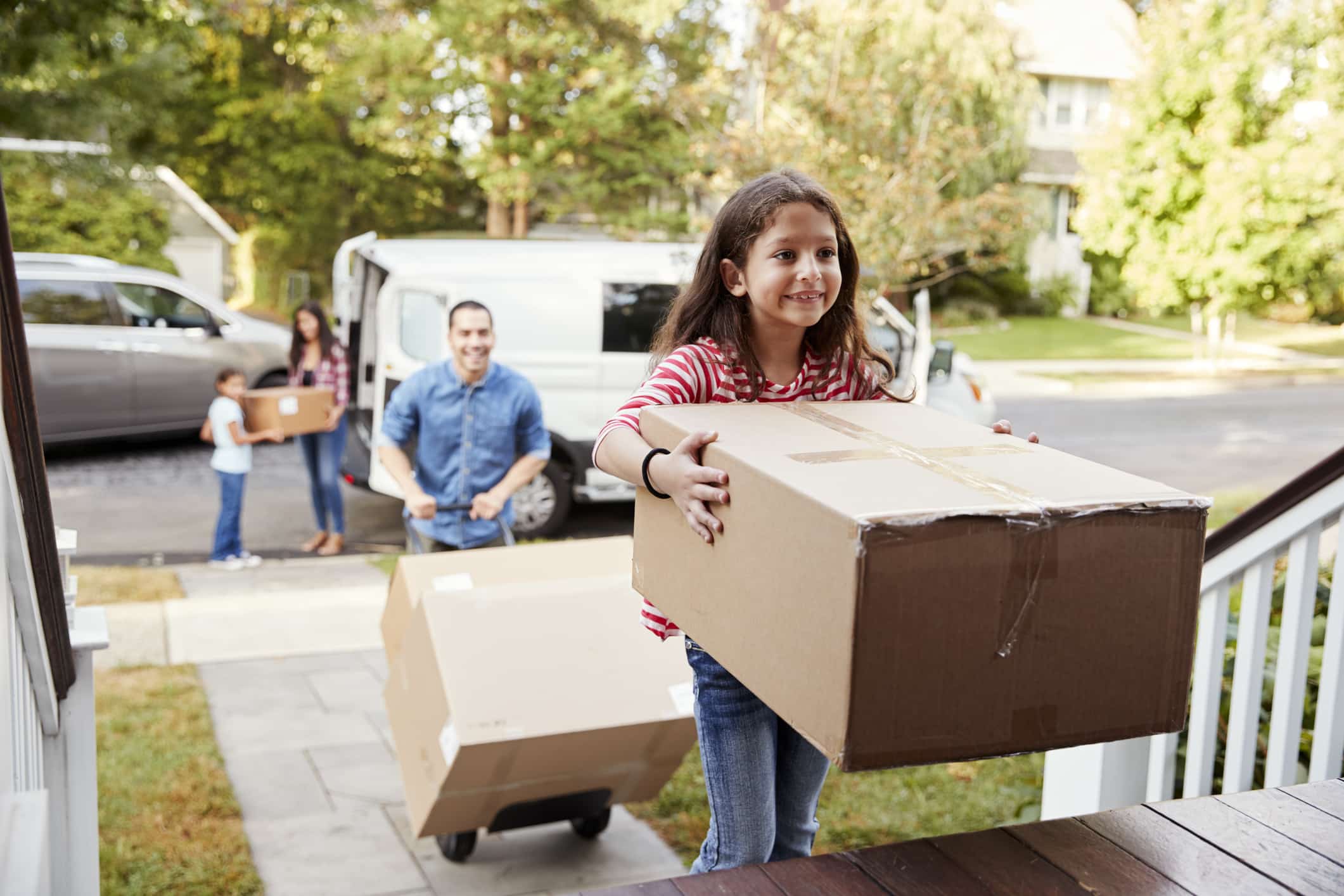 Family carrying boxes into their new home after moving out of state