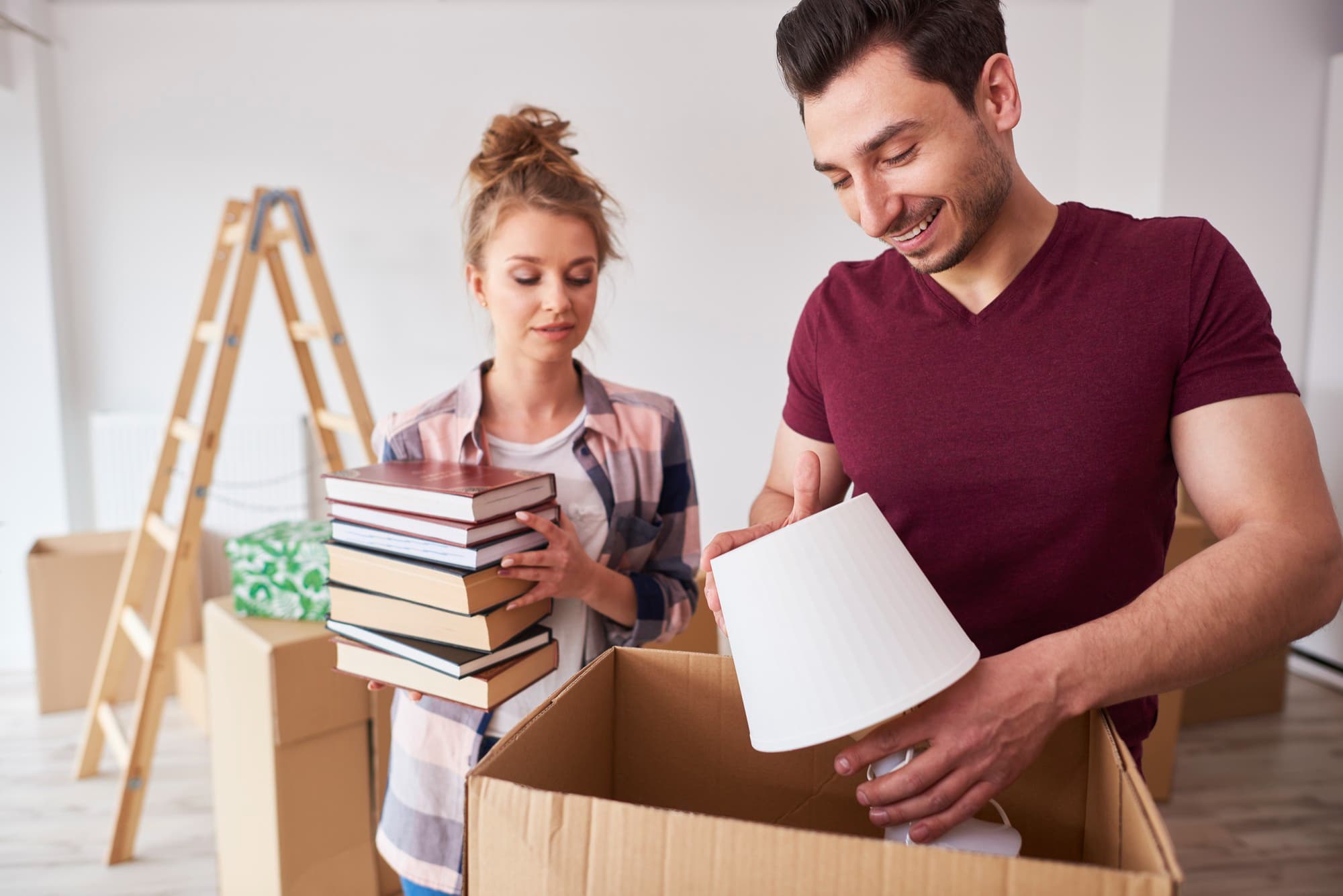 A man and a woman packing books and a lamp before moving out of state