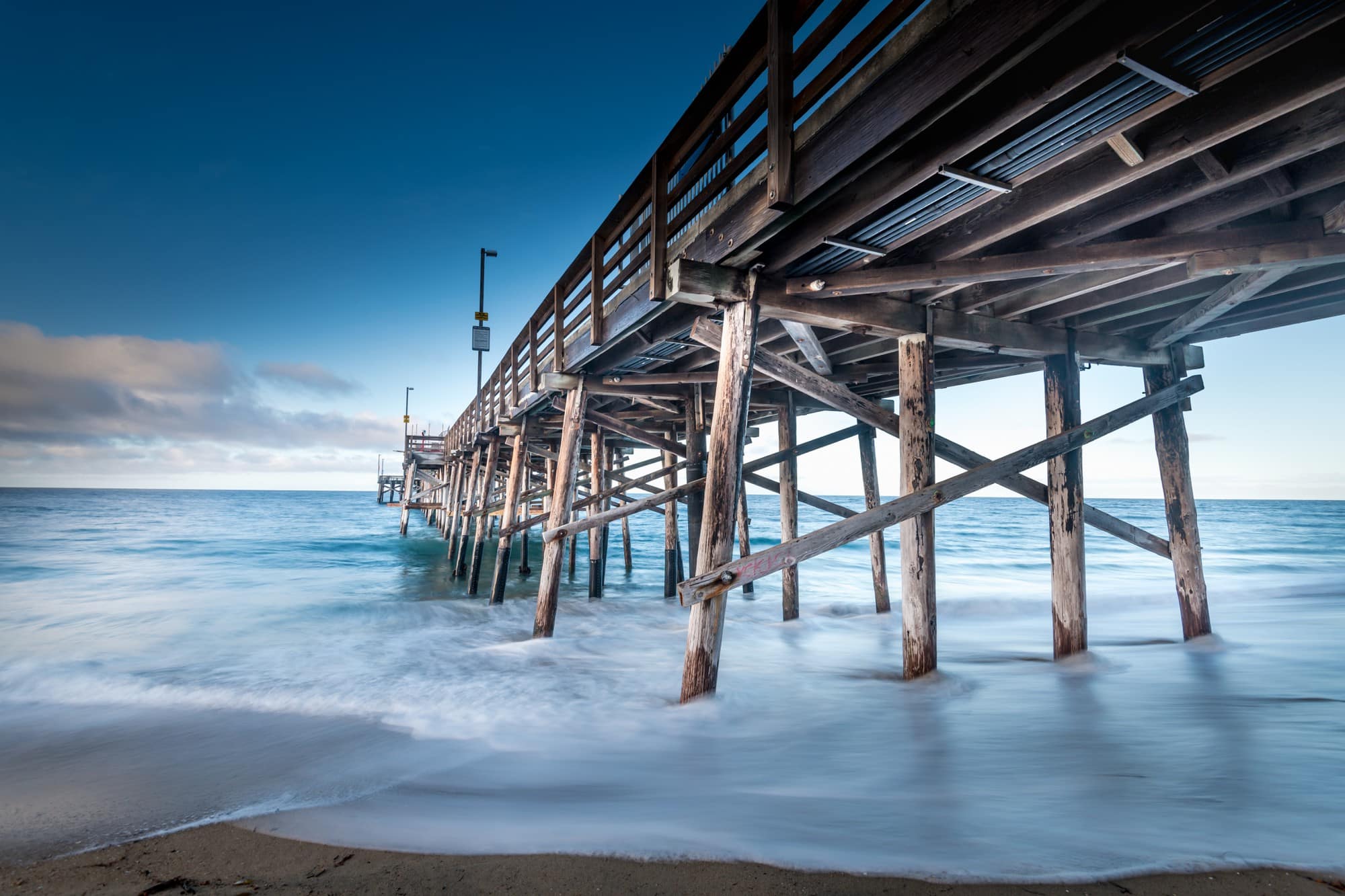 People moving to California enjoy the beaches, such as this on with a wooden pier with waves gently crashing below