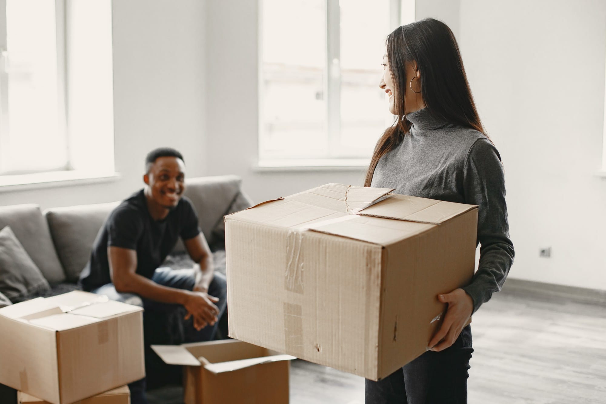 A smiling couple packing their belongings, getting ready to move to New Jersey