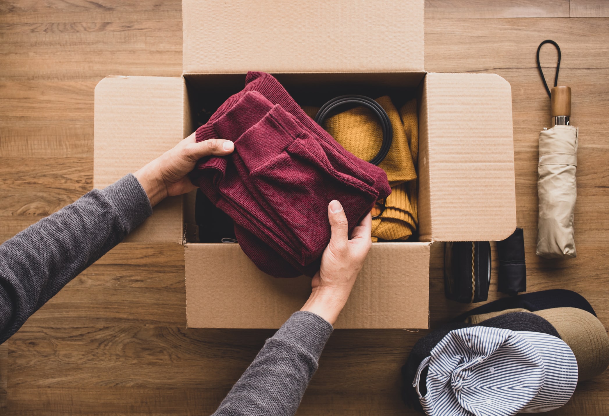 Person carefully placing a folded sweater into a moving box, demonstrating how to pack for a move efficiently