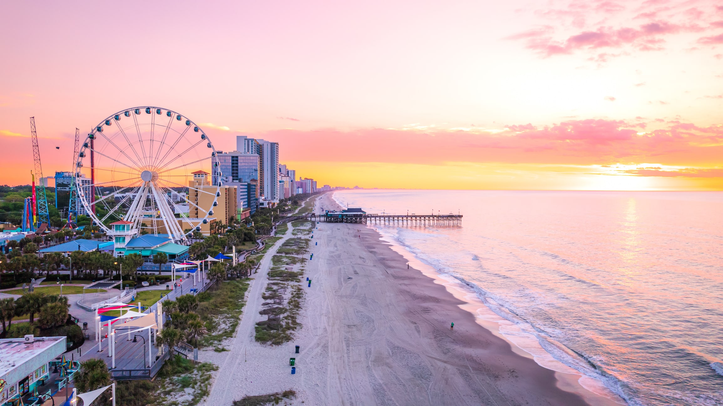 A stunning sunrise over Myrtle Beach with a Ferris wheel and pier, showcasing the appeal of moving to South Carolina