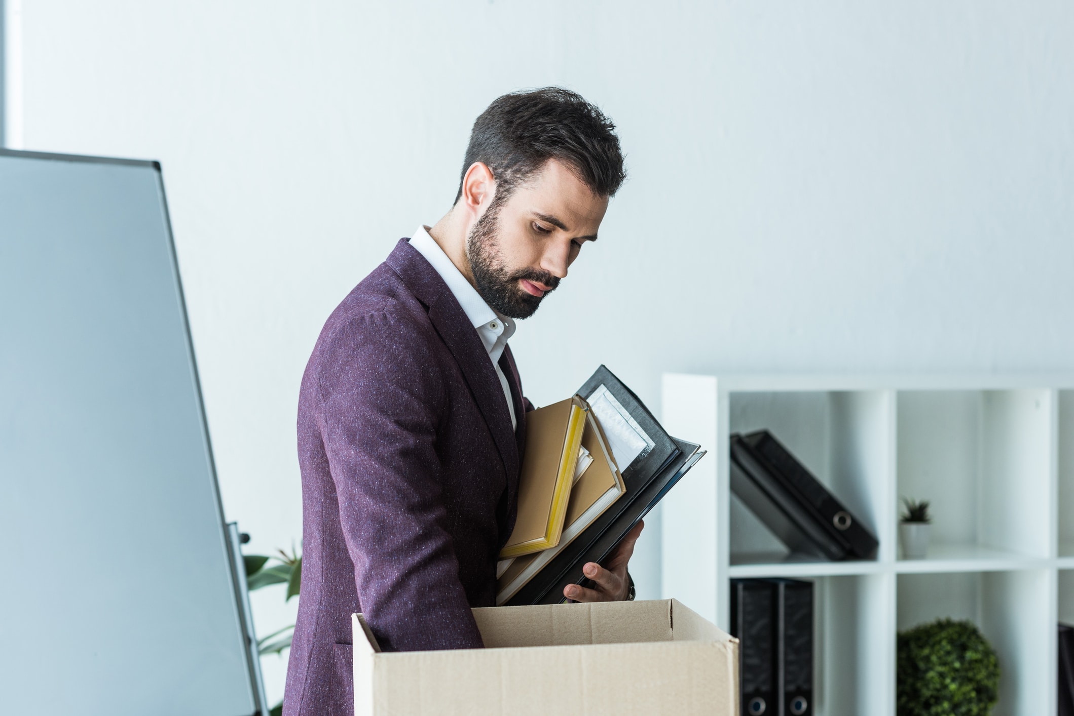 A man placing books from his bookshelf into a moving box 