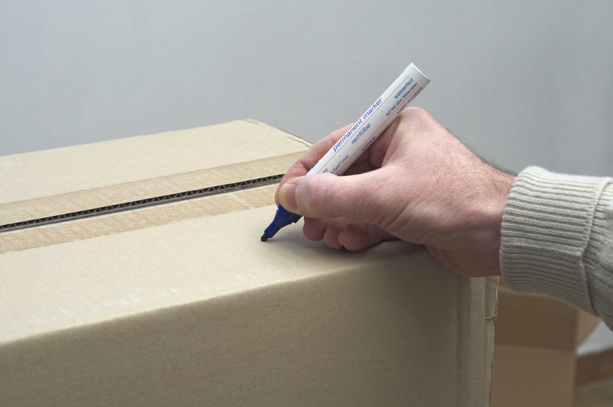 A man labeling a moving box after packing the dishes for moving