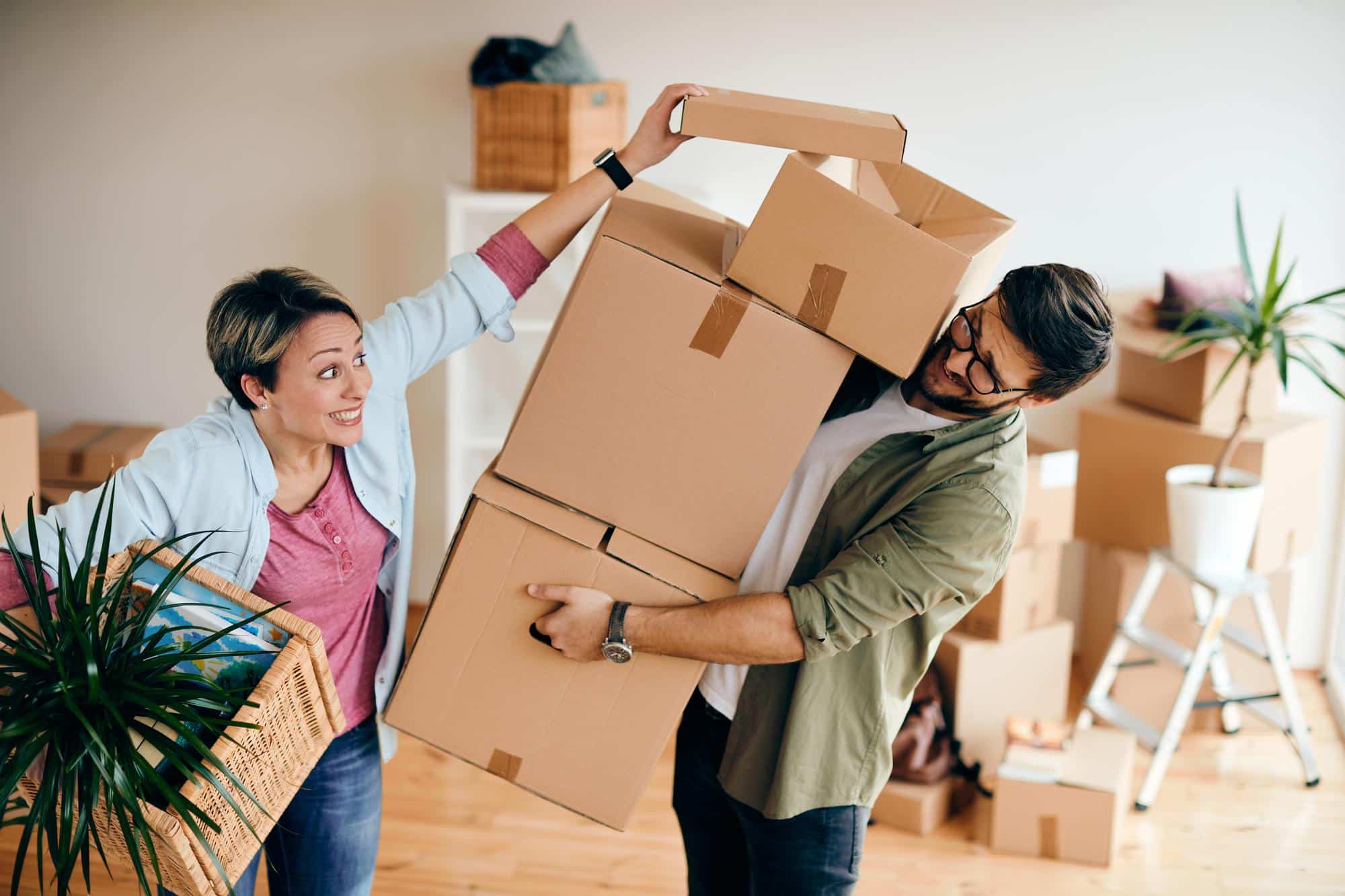 Couple laughing and packing boxes, preparing for their move to Brooklyn