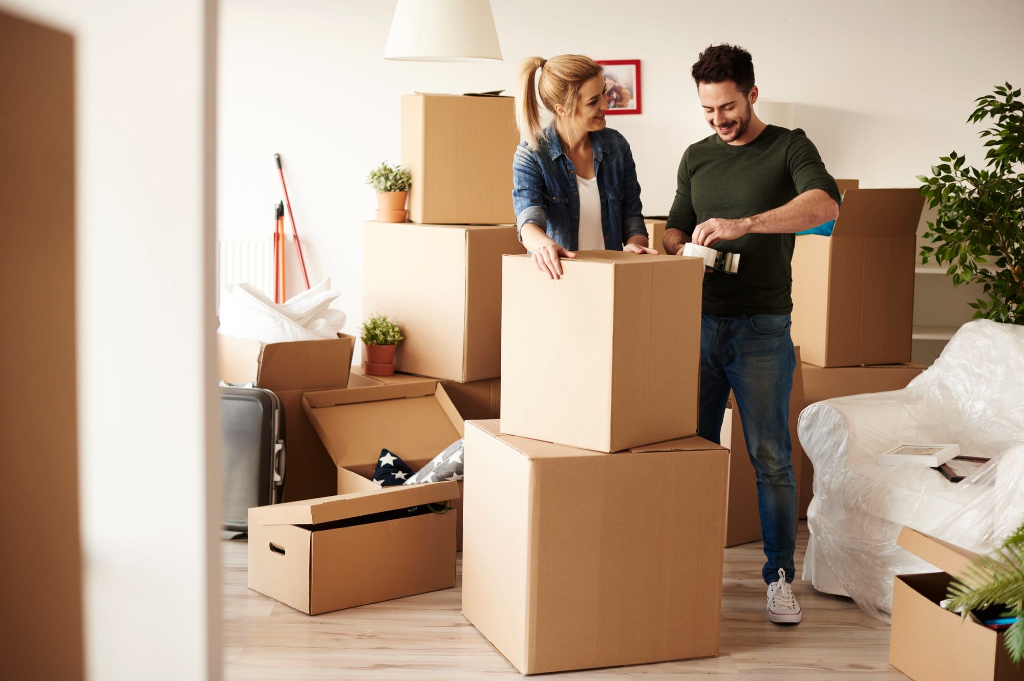 Couple taping up a box while packing for their move, preparing for a fresh with a move to Brooklyn