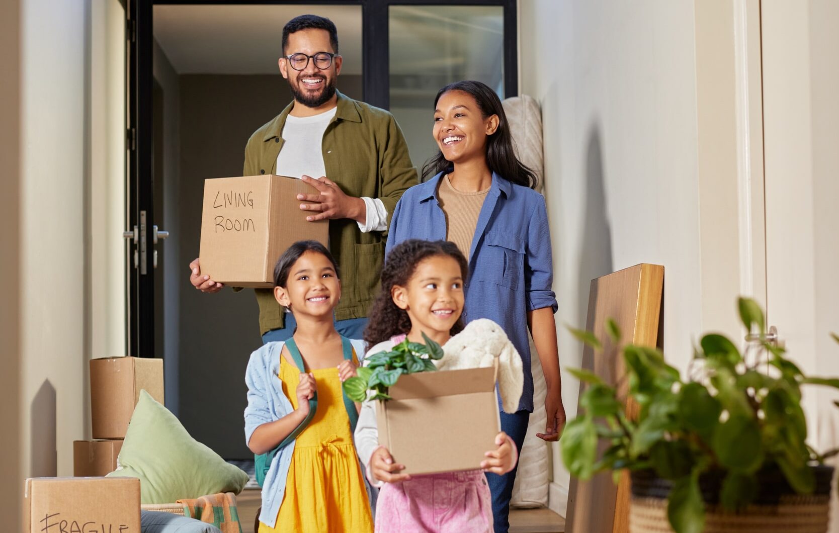 A happy family moving to North Carolina, carrying moving boxes into their new home