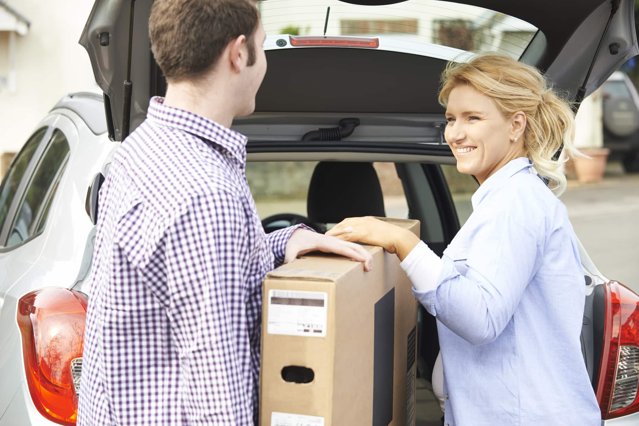 A couple loading their TV, securely packed in a moving box