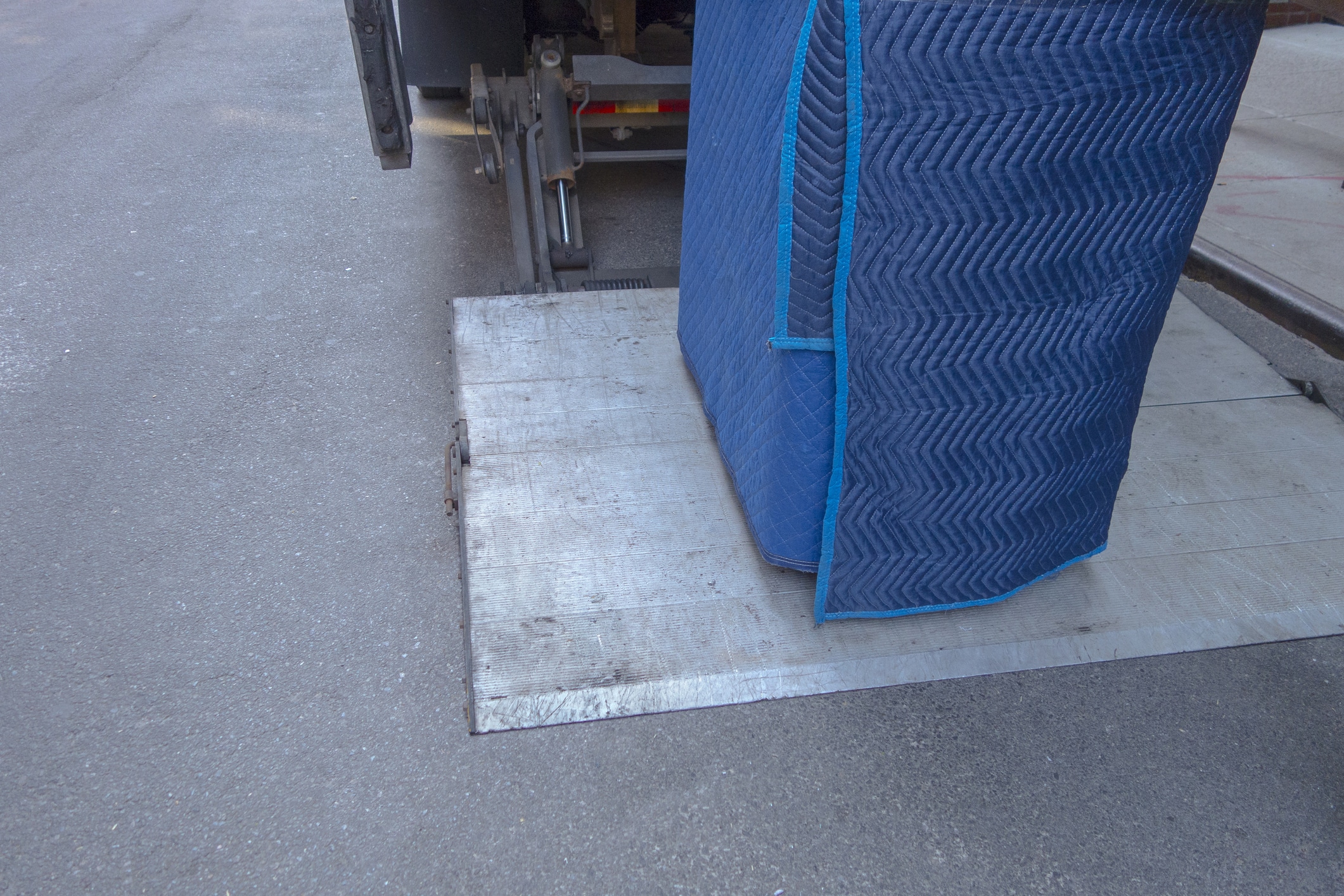 A carefully wrapped and protected piano about to be loaded onto a truck