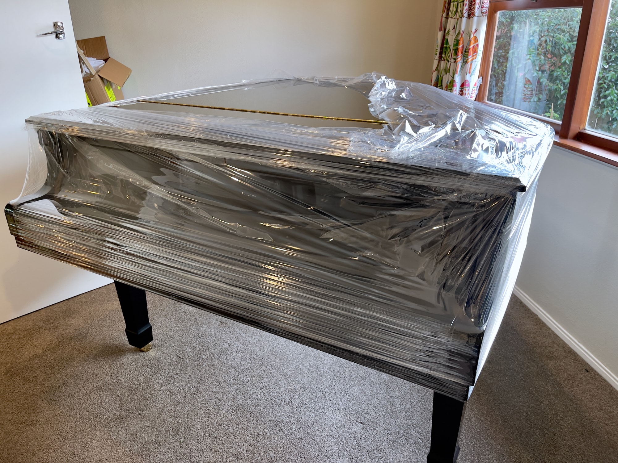 A grand piano wrapped in stretch wrap to protect it from scratches