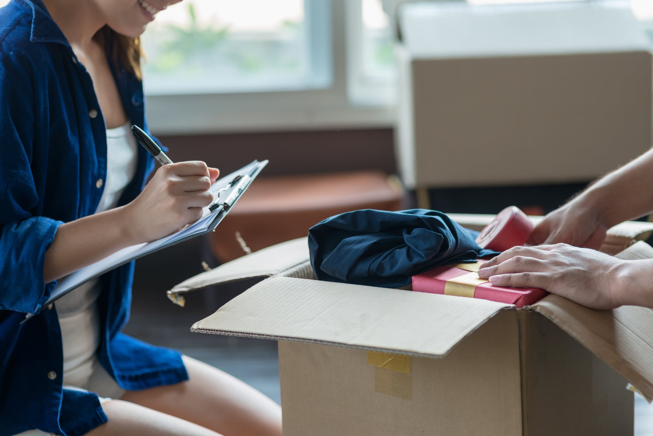 Two people ticking off their moving checklist as they pack their belongings for a job relocation