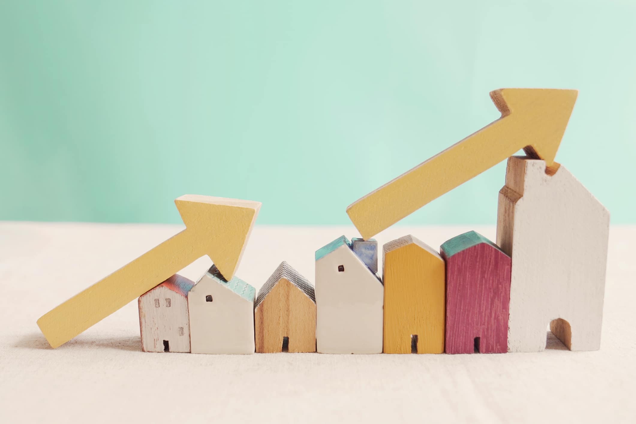 Wooden houses with yellow arrows pointing up. Indicating rising housing prices, which drives Americans to move