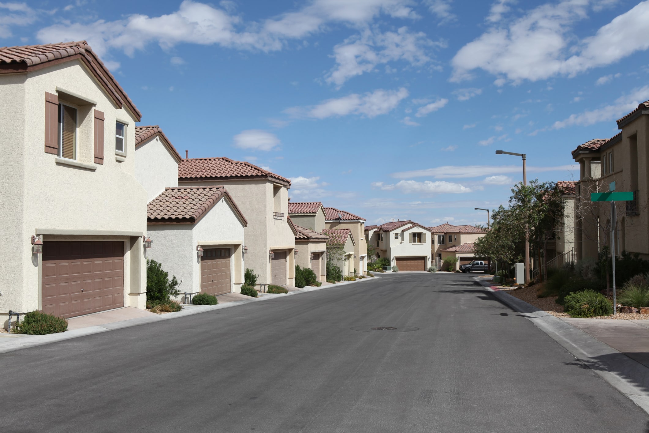 Vegas Single Family Homes A street lined with suburban Southwest-style homes in Las Vegas, featuring stucco exteriors and tiled roofs.