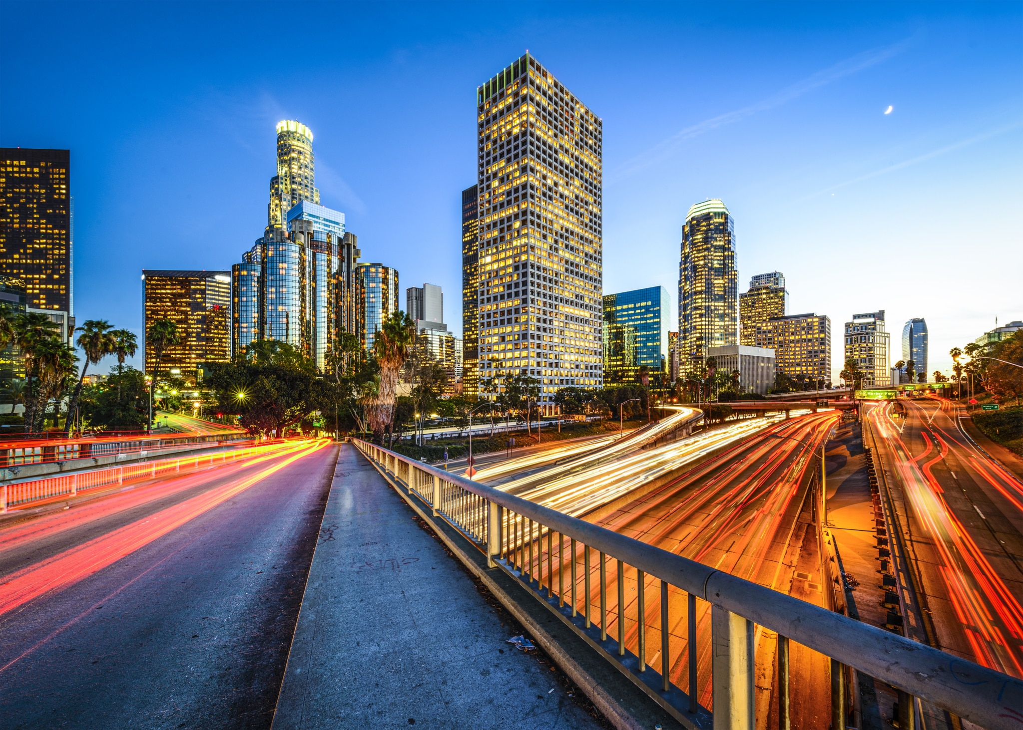 Downtown LA Nighttime view of the Los Angeles skyline, captured from an overpass, with blurred light trails from vehicle traffic