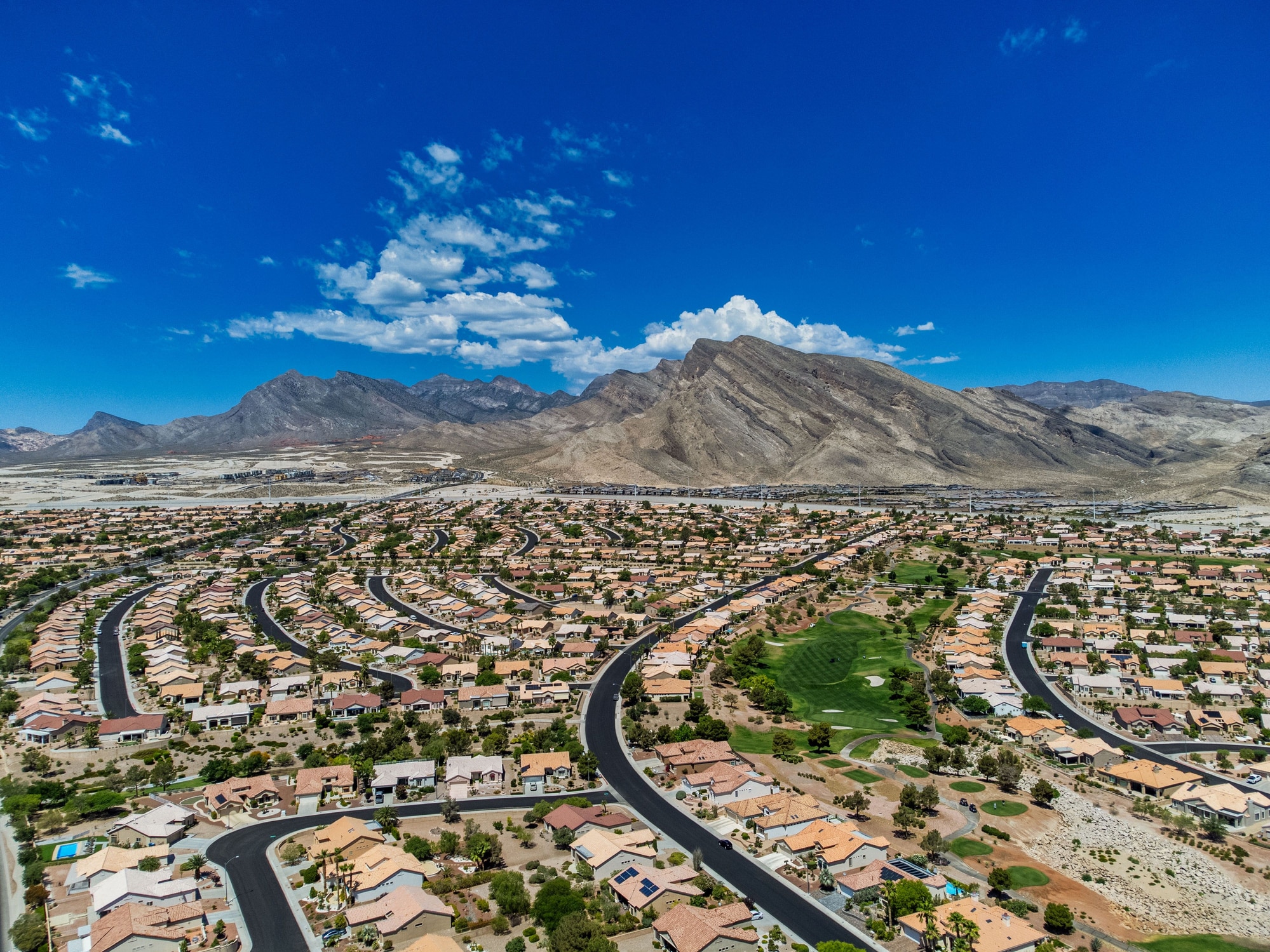 Aerial shot of the Summerlin under a blue sky and sunlight in Las Vegas, Nevada Aerial view of a beautiful neighborhood in Las Vegas with a mountainscape in the background