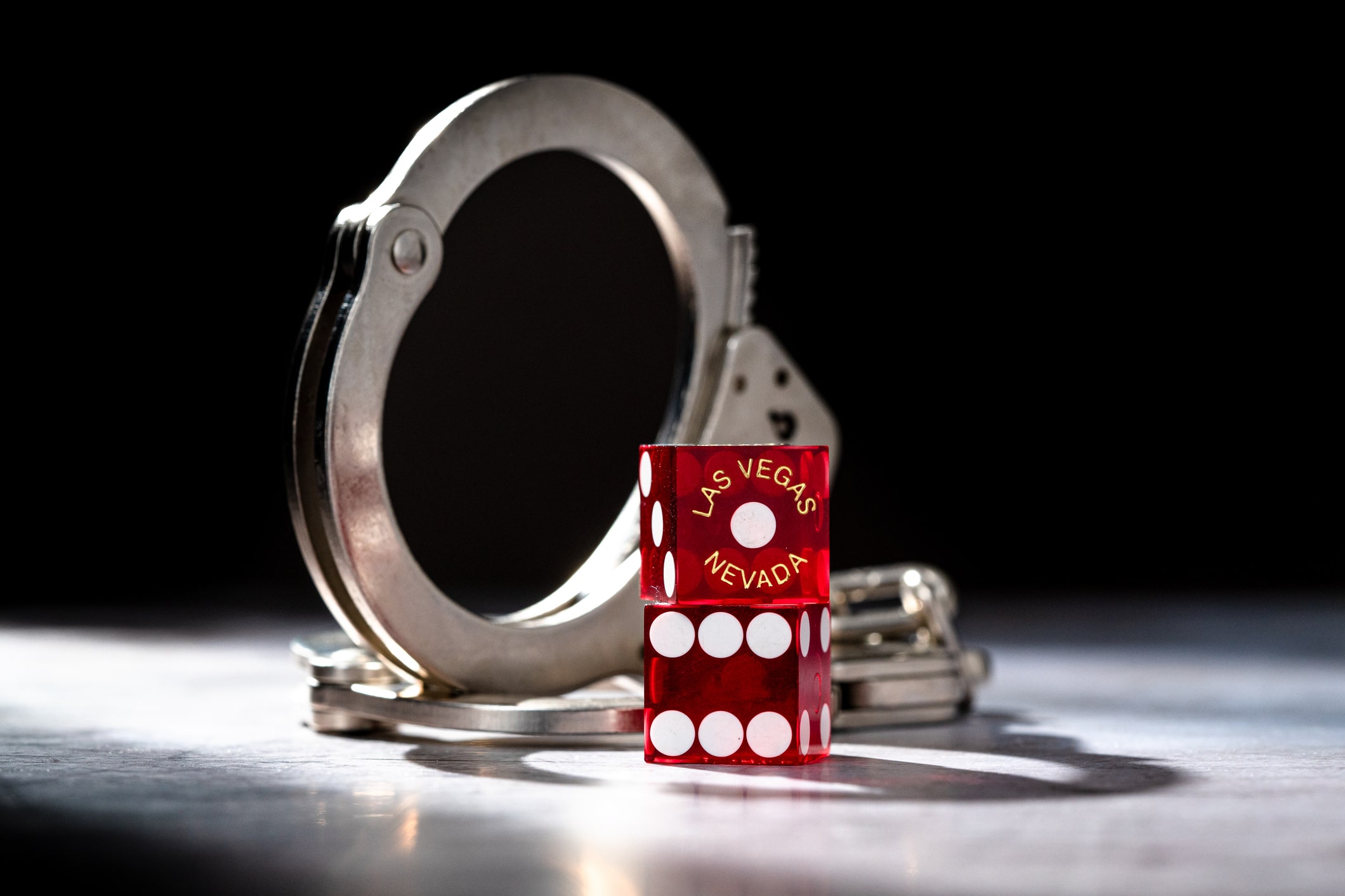 Las Vegas Nevada Craps Dice with Snake Eyes in the Shadow of Hand Cuffs in Jail A shot of a handcuff and 2 dice with one marked “Las Vegas, Nevada”
