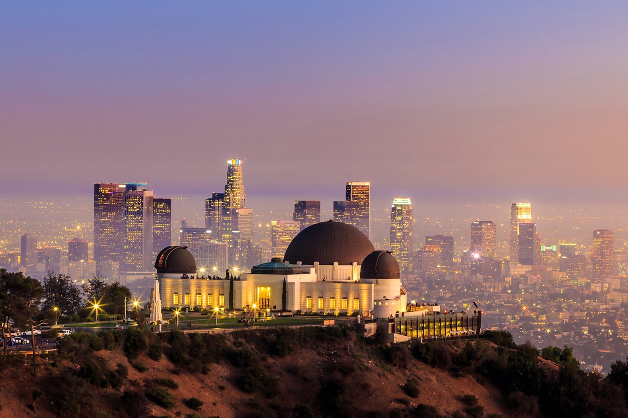 The Griffith Observatory and Los Angeles city skyline The Griffith Observatory illuminated and standing prominently on a hill, against the backdrop of the city skyline at dusk