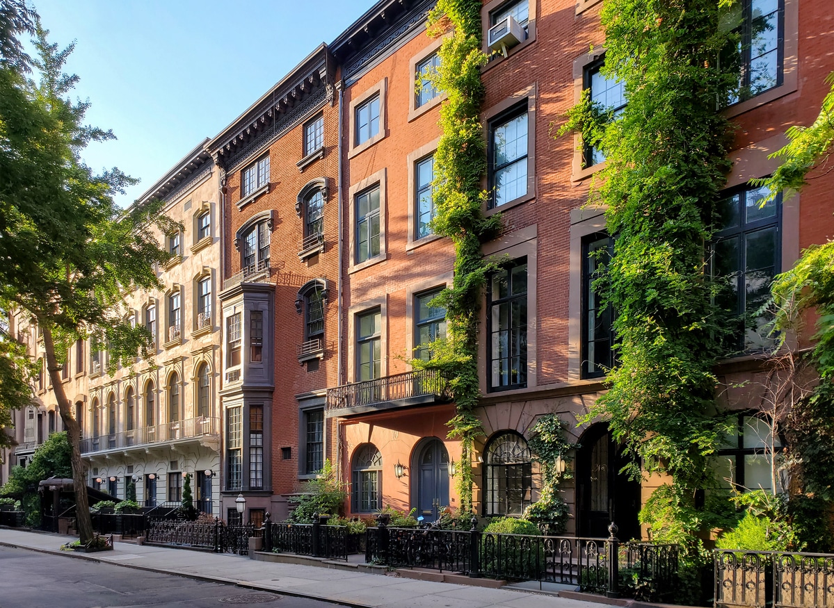 Historic block of apartment buildings on 9th Street in the Greenwich Village neighborhood of Manhattan in New York City A row of brownstone houses in New York City with climbing vines on some of the buildings