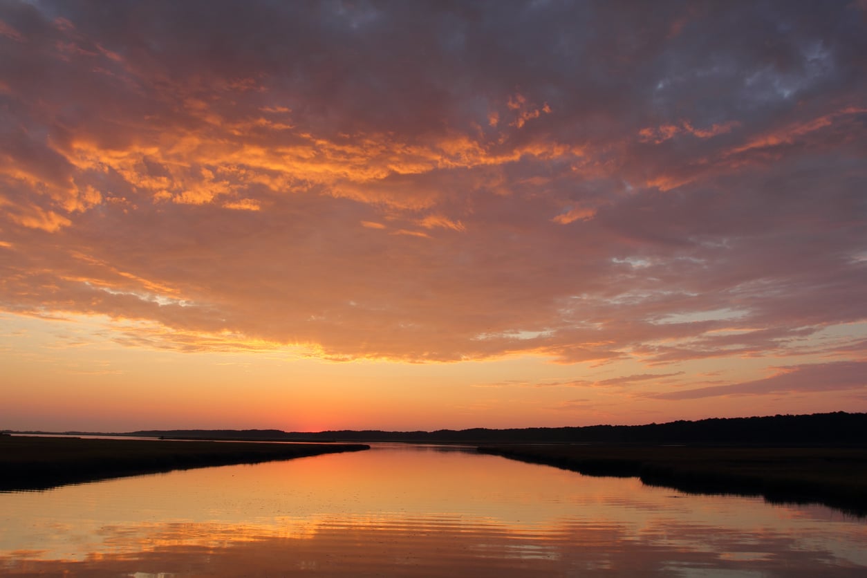 Morning glow at Chincoteague Orange and purple sunset over a marshland in Virginia, the landscape silhouetted against the bright sky