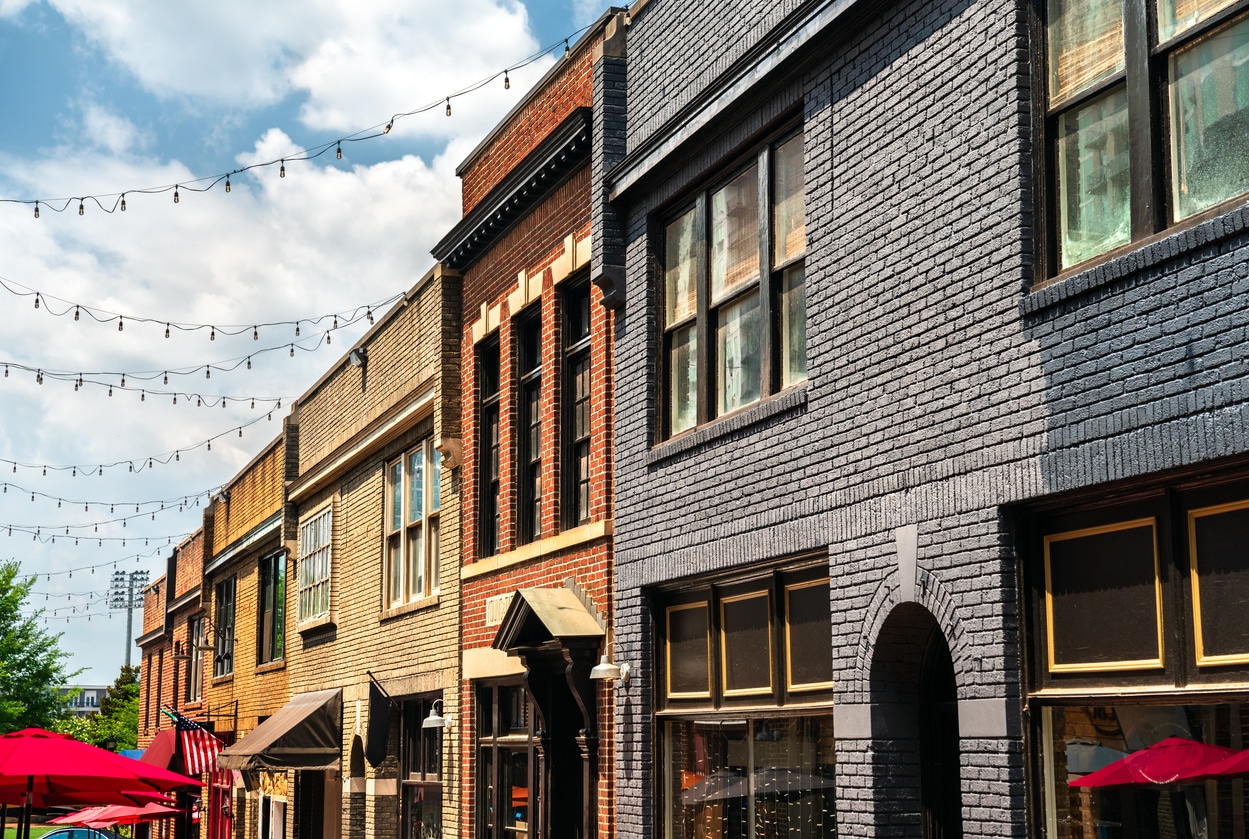 A row of colorful brick buildings along Brevard Court in Uptown Charlotte with string lights hanging above the alleyway