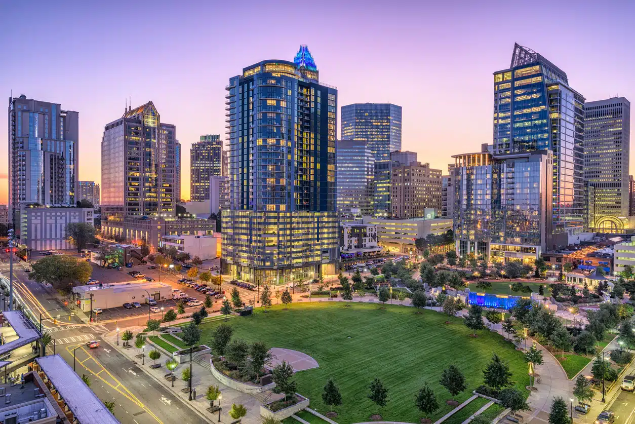 Charlotte, North Carolina, at sunset, featuring the Ascent Uptown building and a spacious park with a green lawn