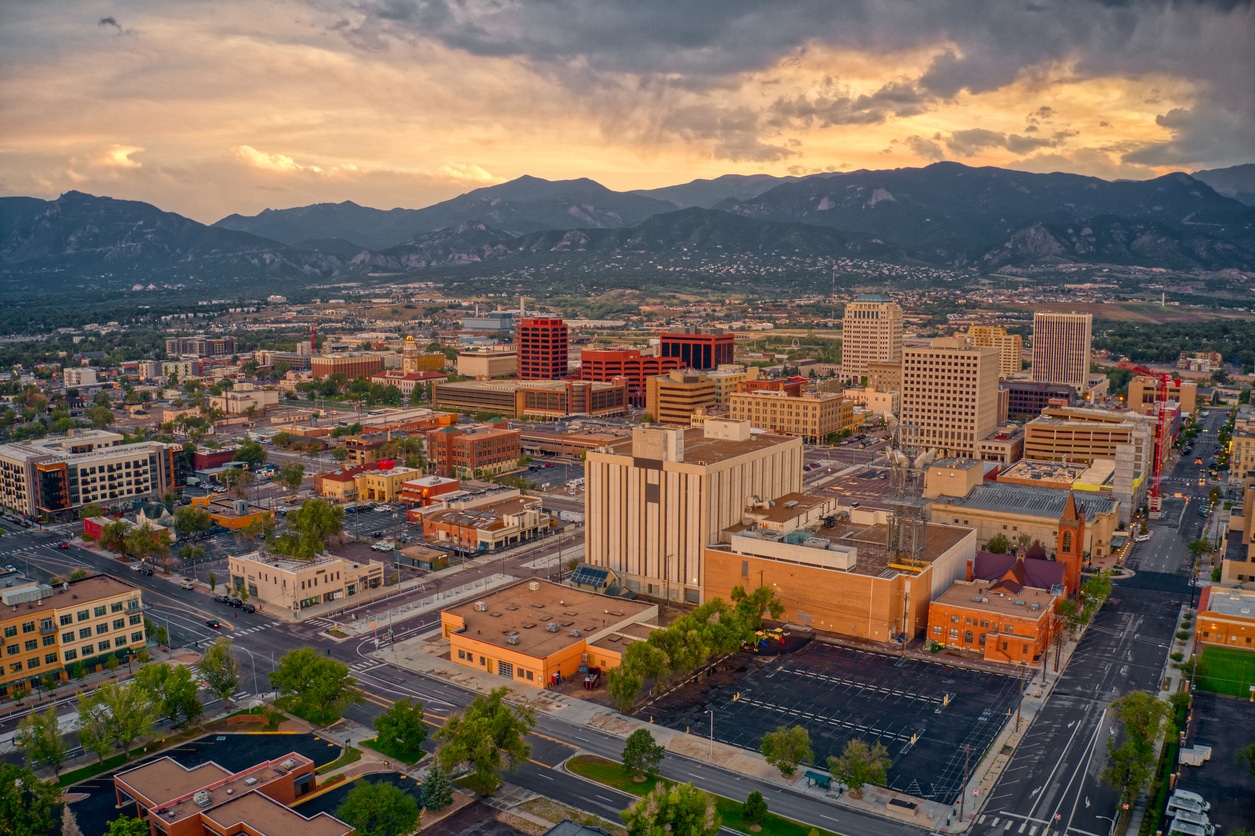 Colorado Springs cityscape at dusk, with the Rocky Mountains and Pikes Peak in the background